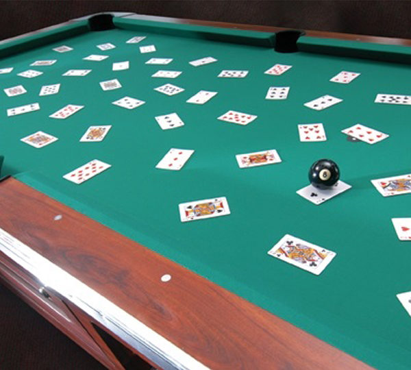 A pool table with playing cards on it.